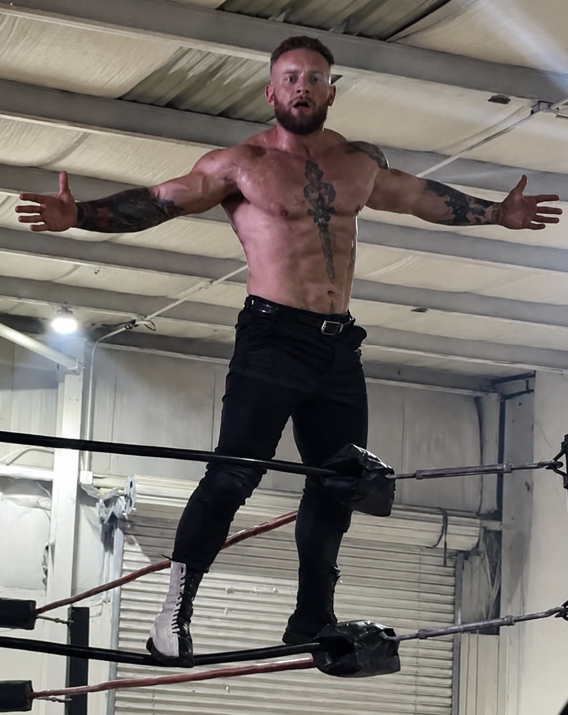 Nyles Cruz as Sabertooth standing on the ring ropes during a live wrestling match